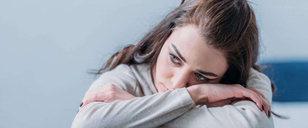 Eine Frau legt traurig und nachdenklich den Kopf auf ihre Knie