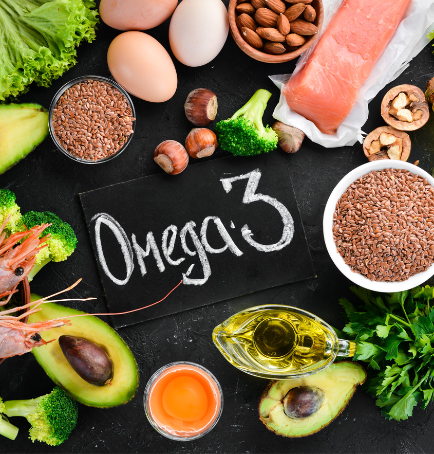 Auf einer schwarzen Schieferplatte steht das Wort "Omega 3", umgeben von reichhaltigen Omega-3 Lebensmitteln