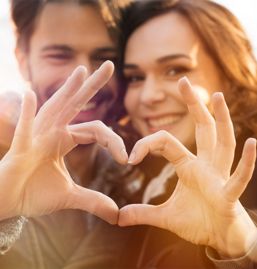 Ein Mann und eine Frau formen zusammen mit ihren Händen ein Herz