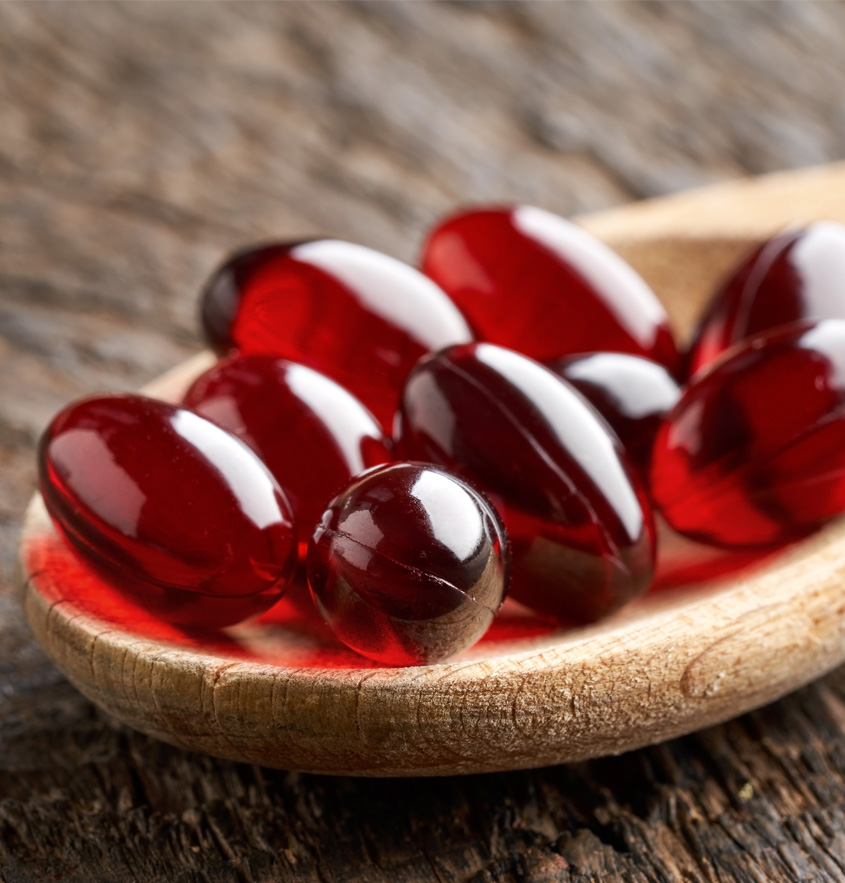 Rote Krillöl Kapseln liegen auf einem Kochlöffel