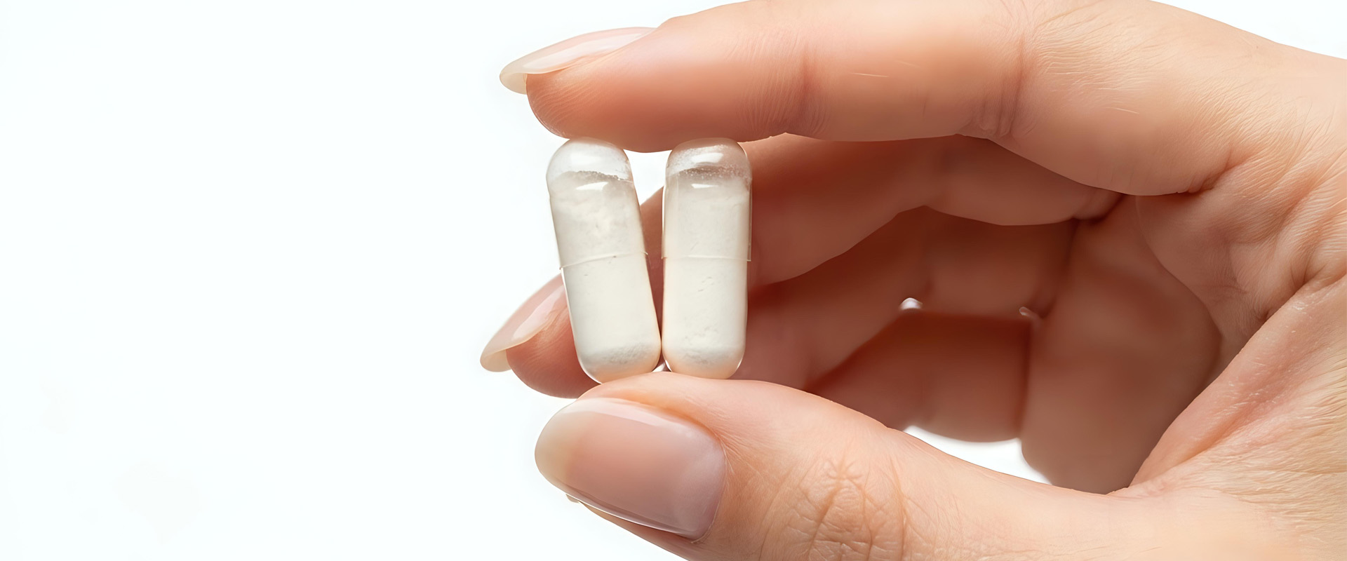 Die Finger einer Frau halten zwei weiß gefüllte Kapseln