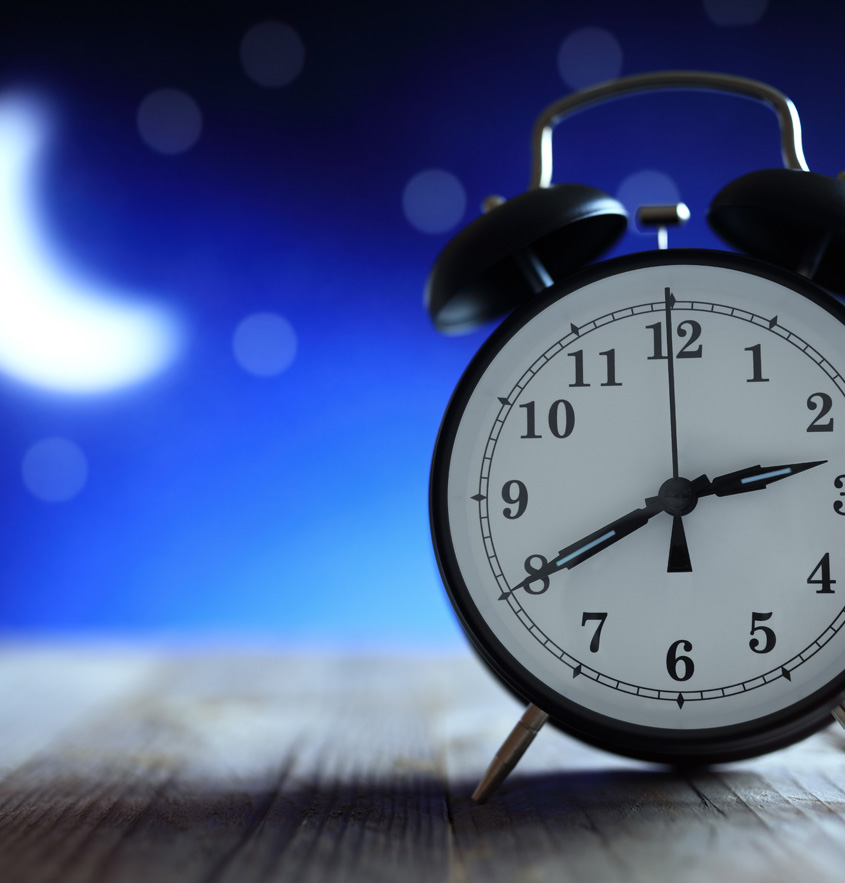 Ein Wecker zeigt die Uhrzeit 02:40 Uhr nachts. Im Hintergrund scheint der Mond