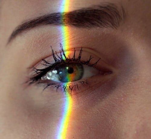 Das Bild zeigt eine Nahaufnahme eines Auges auf das ein Regenbogen geworfen wird